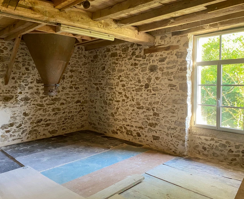 Intérieur d'une maison ancienne en rénovation avec murs en pierre apparente et mortier de chaux