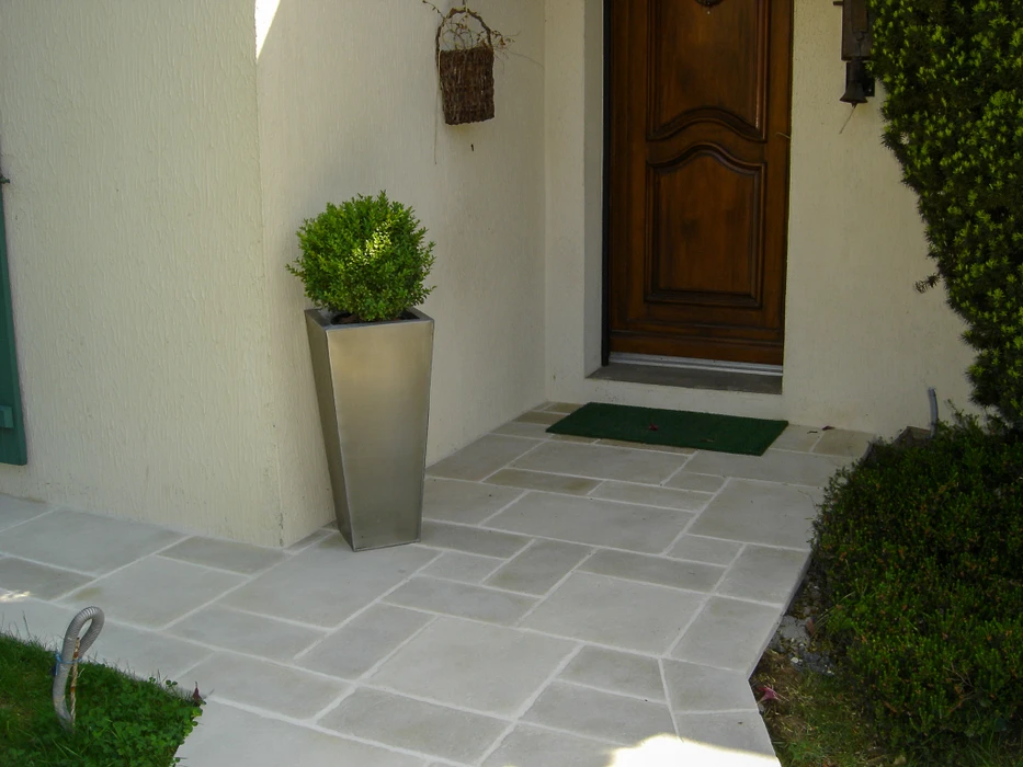 Entrée extérieure résidentielle avec terrasse dallée en pierre naturelle claire, joints blancs