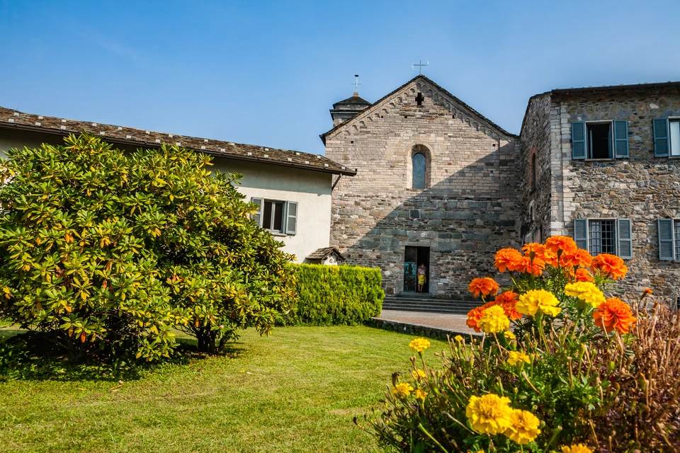 Ouvrier ma&ccedil;on en chemise &agrave; carreaux construisant un mur de briques rouges sur chantier ext&eacute;rieur, skyline urbain en arri&egrave;re-plan flou au coucher du soleil