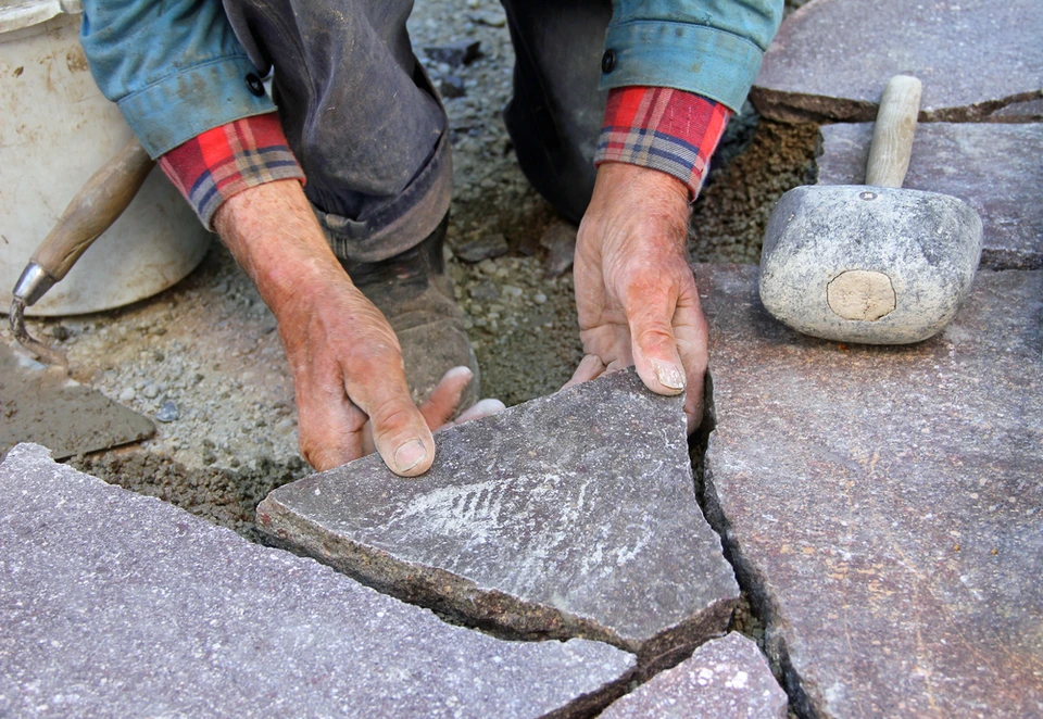 Pile de pierres naturelles de schiste empilées en extérieur, fragments de tailles variées aux teintes violacées et rosées