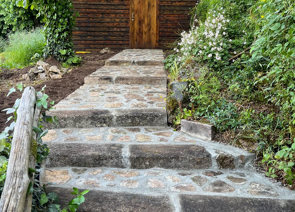 Jardin résidentiel avec mur de soutènement en béton lisse, pelouse entretenue et massif fleuri aux fleurs roses