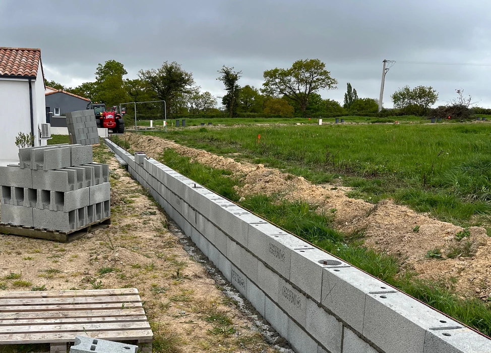 Jardin résidentiel avec mur de soutènement en béton lisse, pelouse entretenue et massif fleuri aux fleurs roses