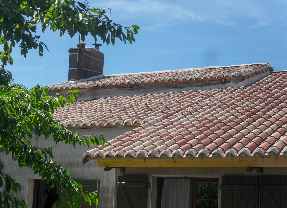 Toiture en tuiles de terre cuite avec lucarne à fenêtre quatre carreaux et encadrement jaune